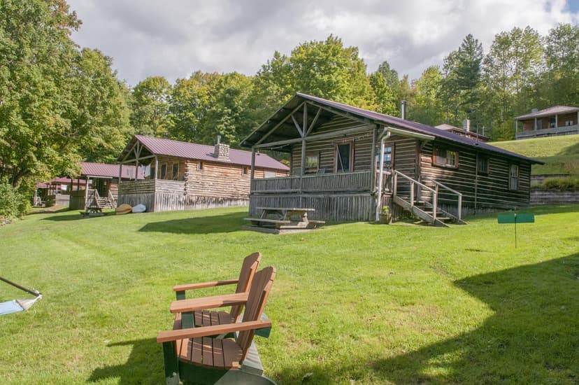 Adirondack chairs facing the rustic log cottages